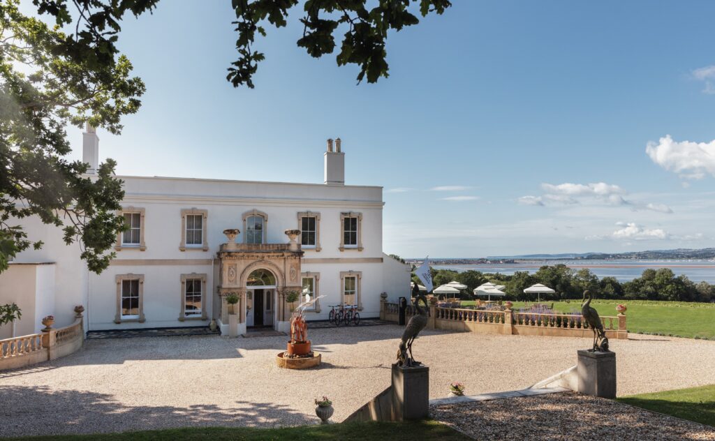 Lympstone Manor Hotel in the summer with view of vineyard in the background